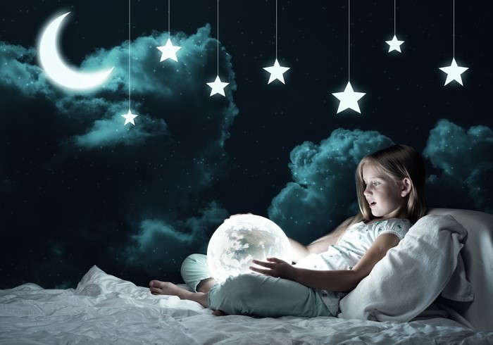 Girl with glowing moon in bed under starry night sky