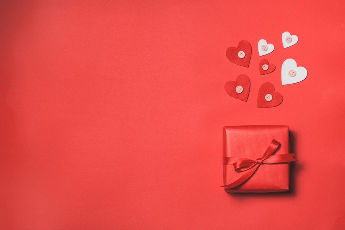 Red gift box with hearts on red background
