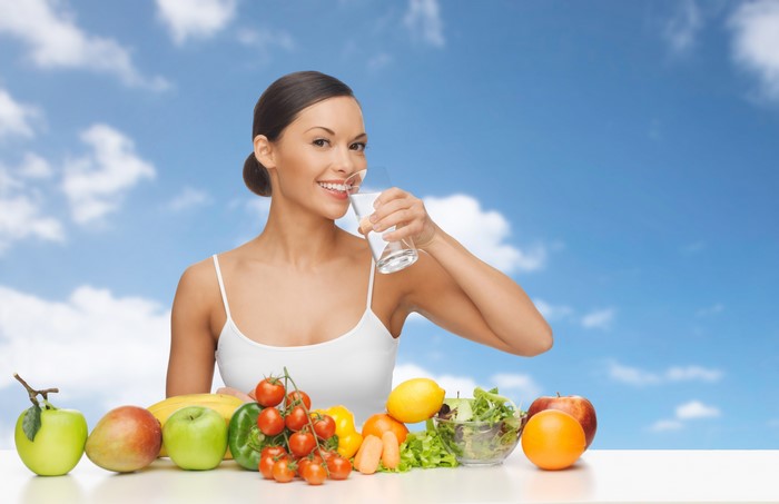 Woman drinking water with fruits and vegetables