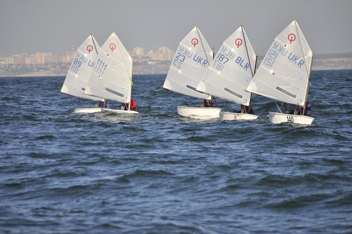 Sailboats racing on the sea with a city in the background