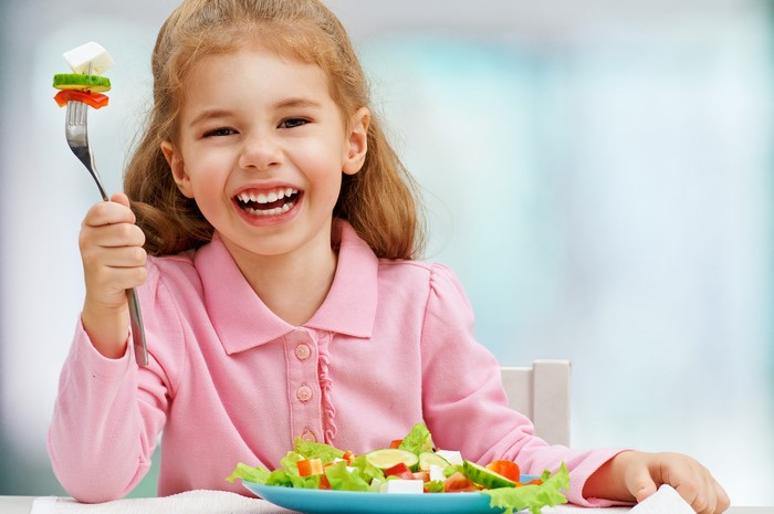 Young girl eating salad with a fork