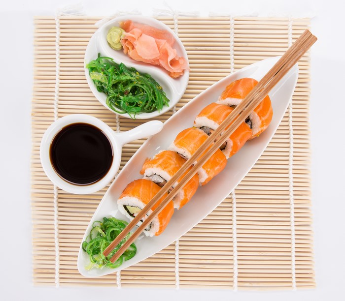 Sushi with Salmon, Soy Sauce, and Accompaniments on Bamboo Mat