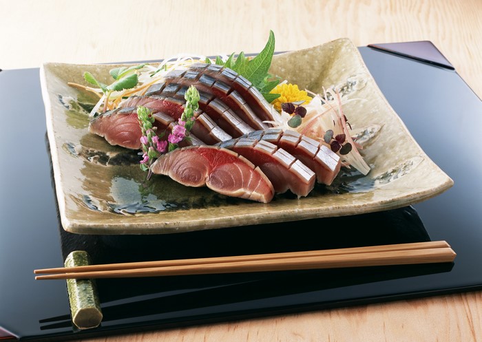 Sashimi on a decorative plate with chopsticks
