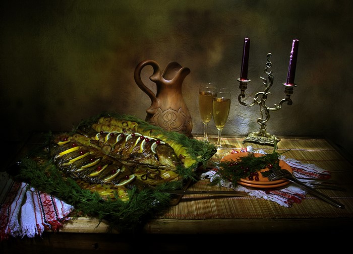 Still life with roasted fish, dill, and candles