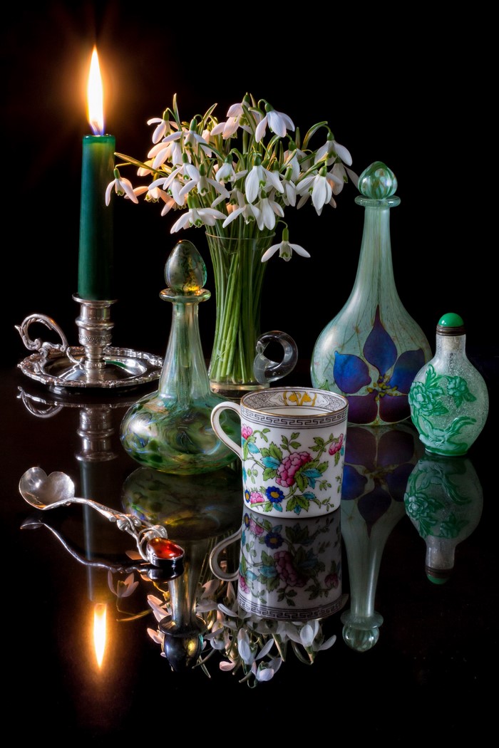 Still-life with snowdrops, candle, cup, and bottles