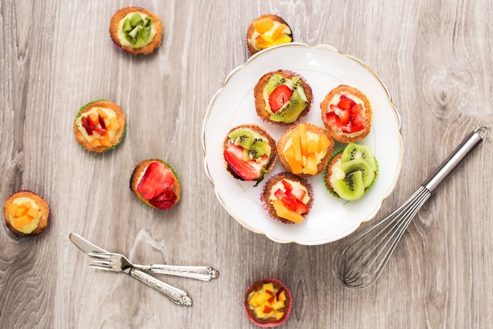 Fruit tarts on a wooden table with a whisk and cutlery