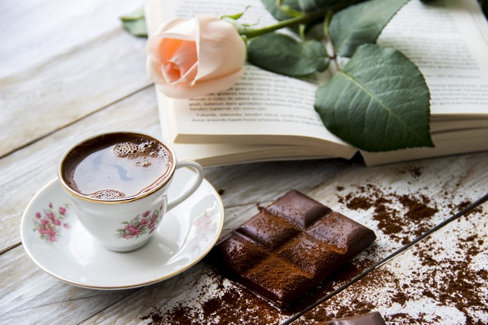 Still-life of coffee, chocolate, rose, and book