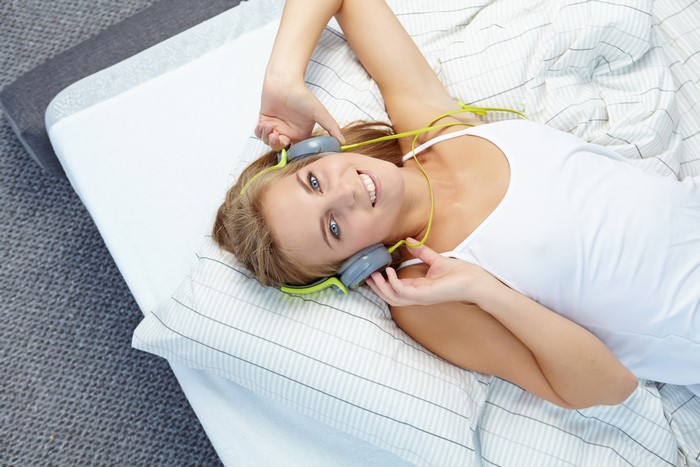 Woman with headphones lying on bed