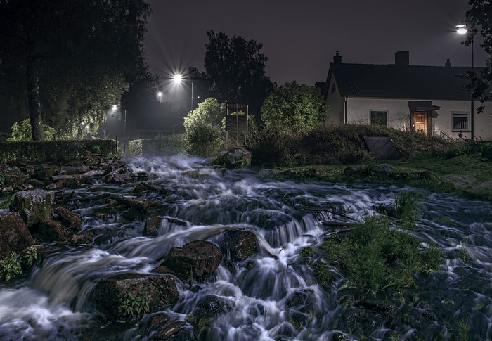 Night scene of a river flowing past houses in Sweden