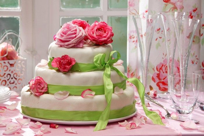 Three-tiered cake with roses and green ribbon