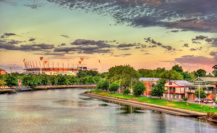 Melbourne stadium and houses along Yarra River at sunset