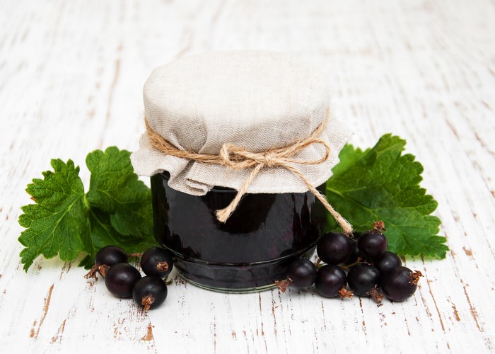 Jar of blackcurrant jam with fresh currants and leaves