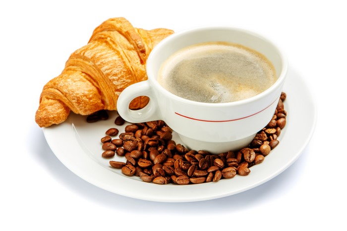 Coffee cup with croissant and coffee beans on a plate