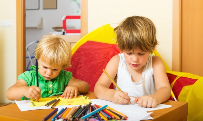 Two children drawing with pencils