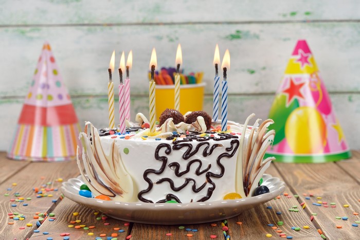 Birthday cake with lit candles and party hats