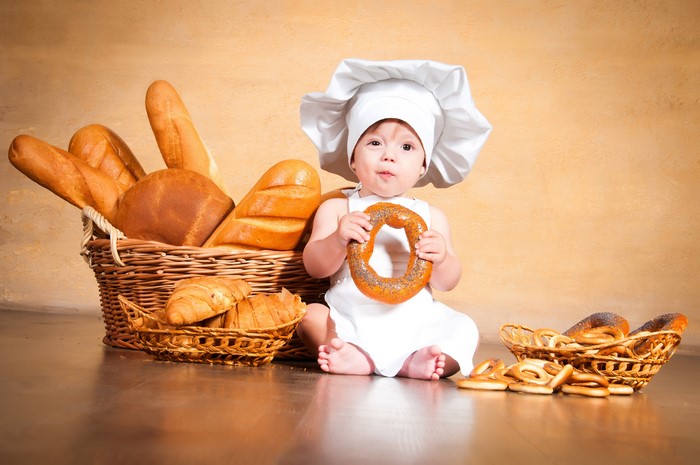 Baby in chef hat with bread and pastries