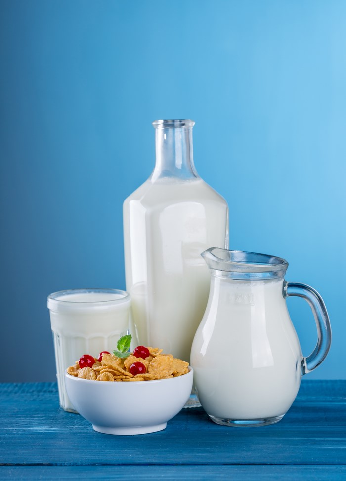 Milk in a bottle, jug, and glass with cereal