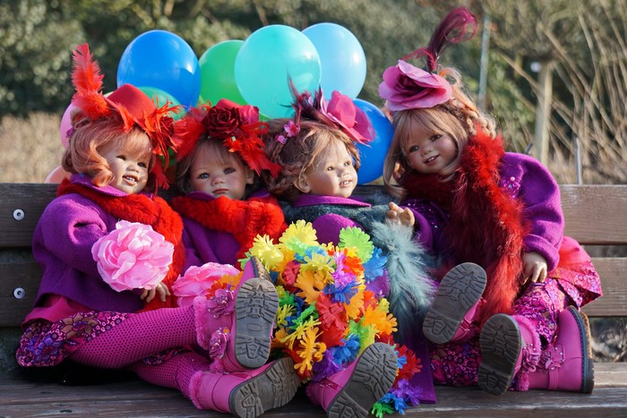 Four dolls with balloons and flowers in a park