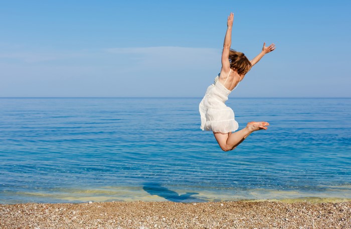 Woman in white dress jumping on a beach