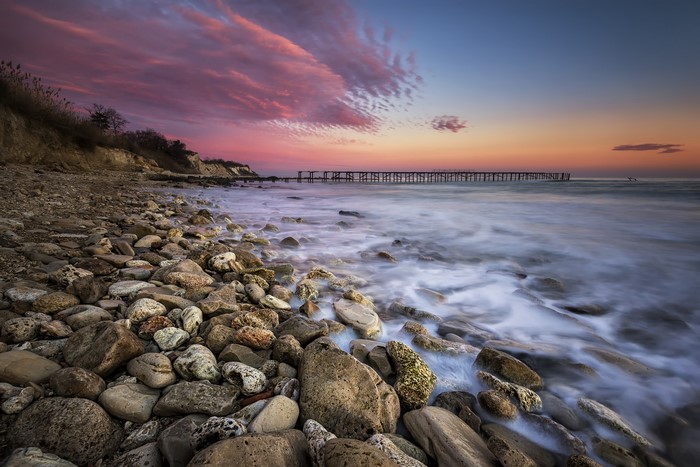 Rocky beach with pier at sunset