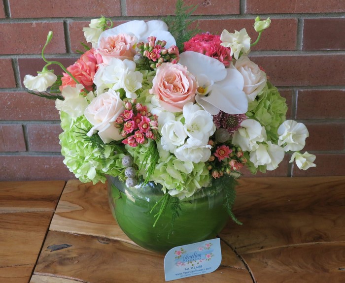 Floral arrangement with roses, orchids, and hydrangeas in a glass vase