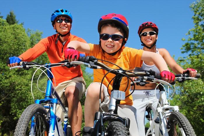 Family cycling with helmets and sunglasses
