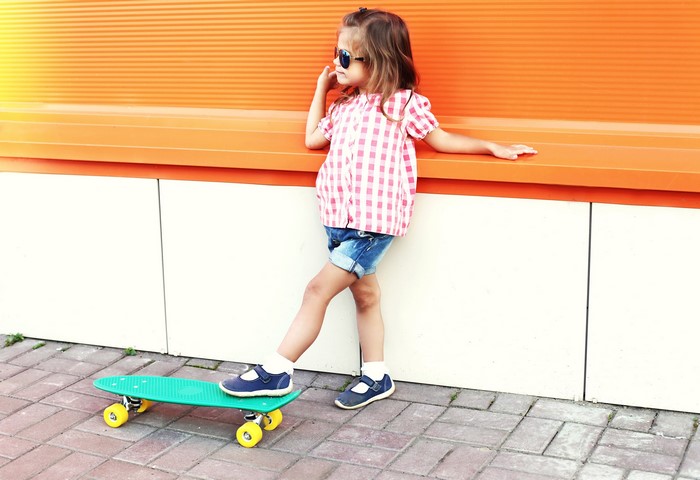 Little girl with sunglasses on a skateboard