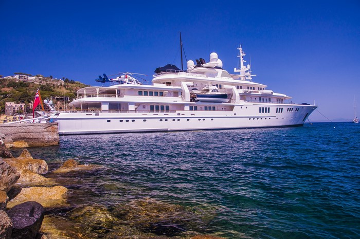 Large white yacht with helicopter docked at marina