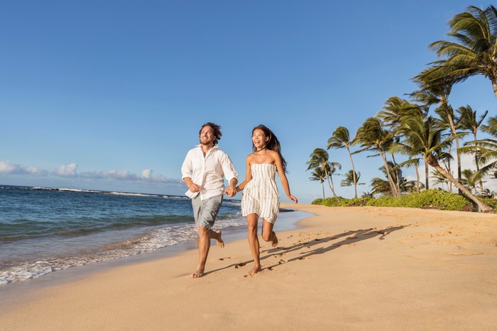 Couple running on a beach with palm trees