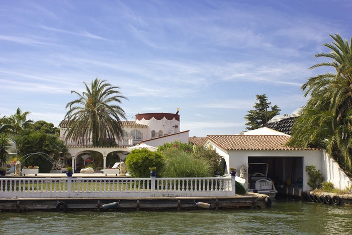Villas and boats on a canal with palm trees