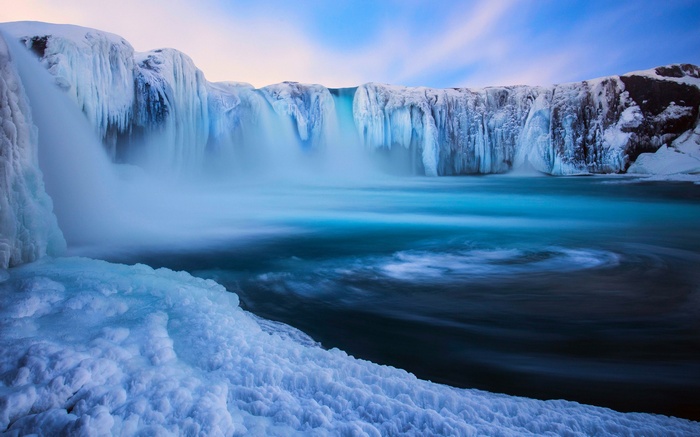 Frozen waterfall with icy formations and blue water