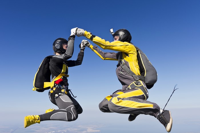 Two skydivers in mid-air giving a fist bump