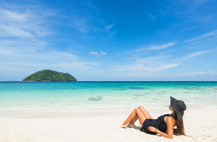 Woman in hat sunbathing on a tropical beach