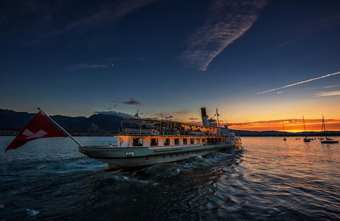 Steamboat with Swiss Flag on Lake Thun at Sunset