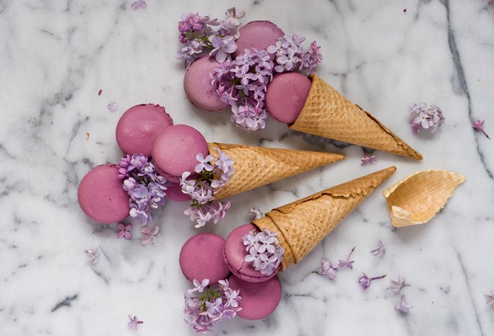Pink macarons with lilac flowers in ice cream cones