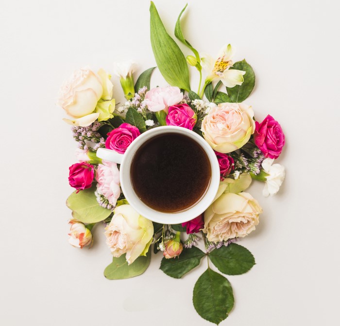 Coffee cup surrounded by roses and carnations