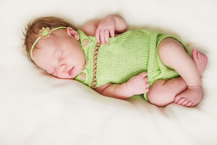 Newborn baby sleeping in a green outfit