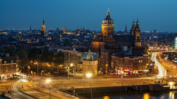 Amsterdam cityscape at night with illuminated buildings and light trails