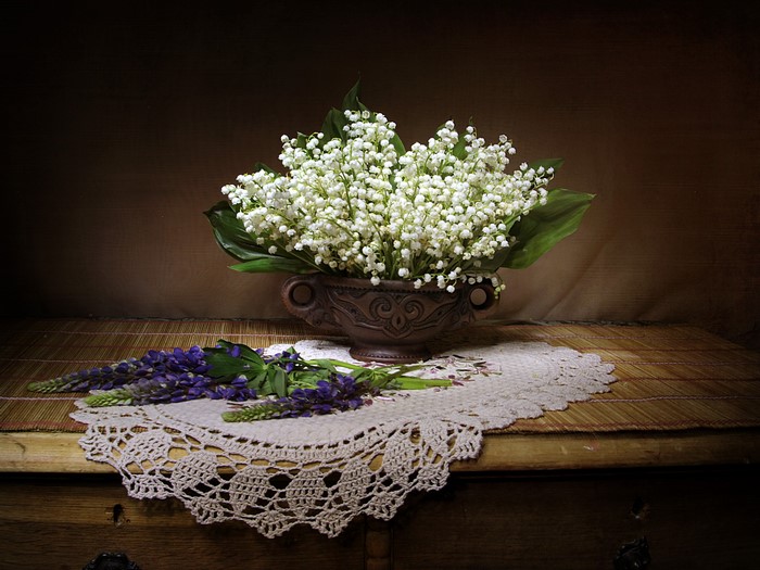 Lily of the valley and lupine flowers in a vase on a table