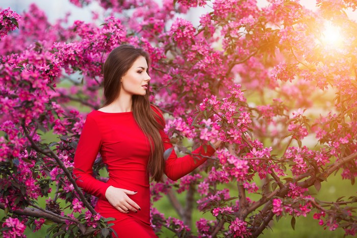 Woman in red dress among flowering trees