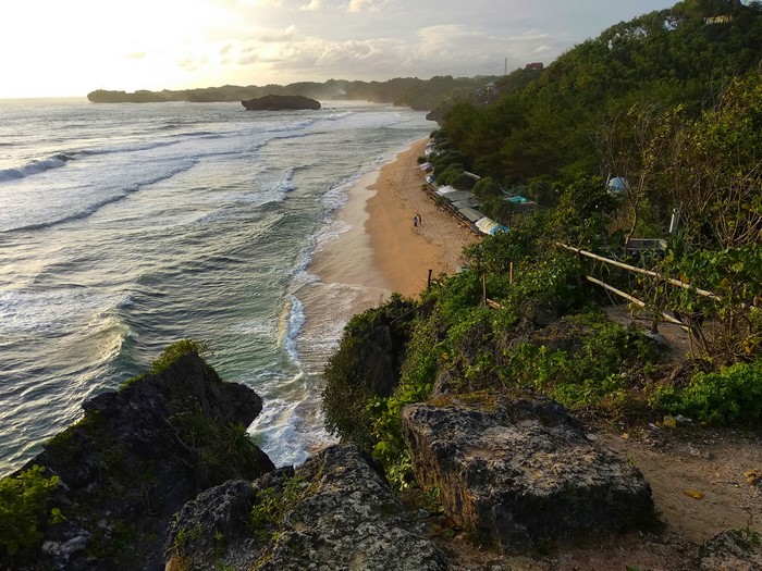 View of a tropical beach with waves and cliffs