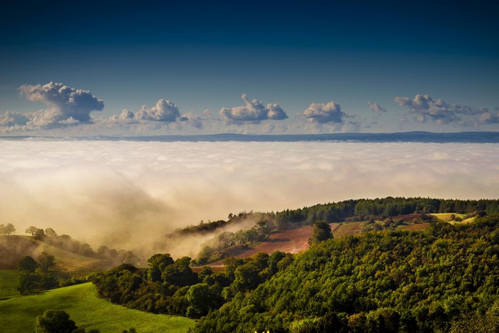 Rolling hills covered in fog with clouds above