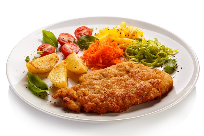 Breaded meat with potatoes, tomatoes, and pasta