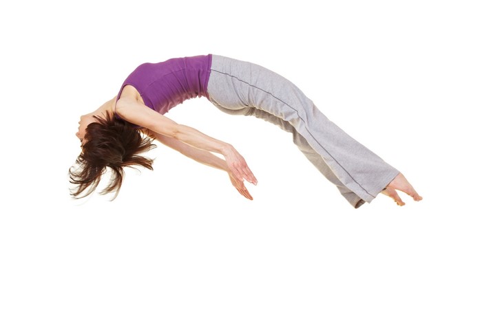Woman in purple tank top and grey pants doing a backflip