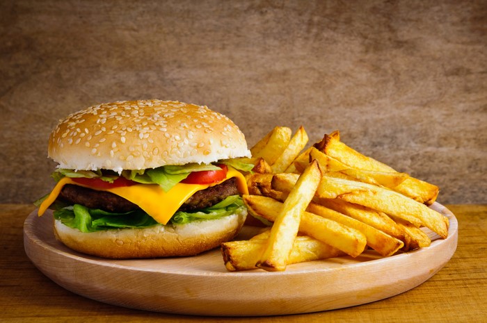 Hamburger and French fries on a wooden plate
