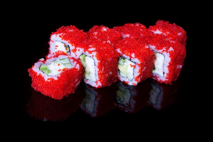 Sushi rolls with red caviar on black background