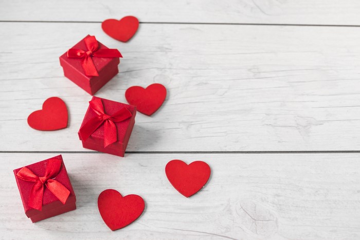 Red gift boxes and hearts on a wooden background