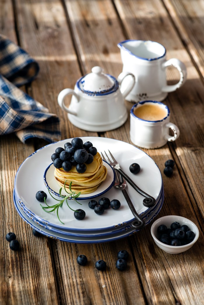 Pancakes with blueberries and coffee on wooden table