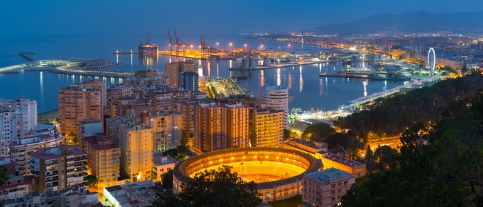 Malaga cityscape with port and bullring at dusk