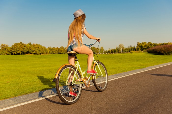 Blonde girl on a bicycle wearing a hat